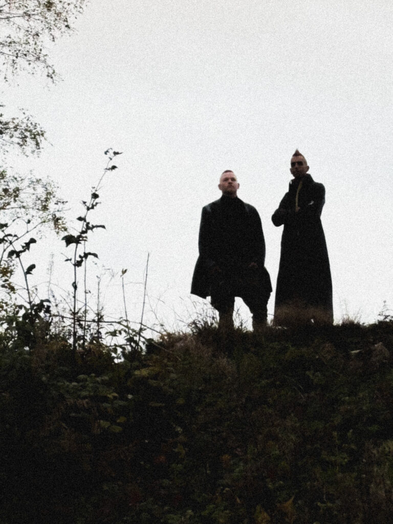 Bandpromofoto Gustav + ph4nt in Mänteln karger Landschaft