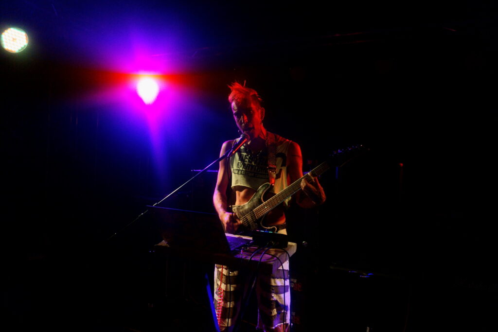 ph4nt mit orangenem Iro & neongrünem "Destroy Everything for a better Tomorrow"-Croptop singt in's Mikro, Croptop spielt Gitarre