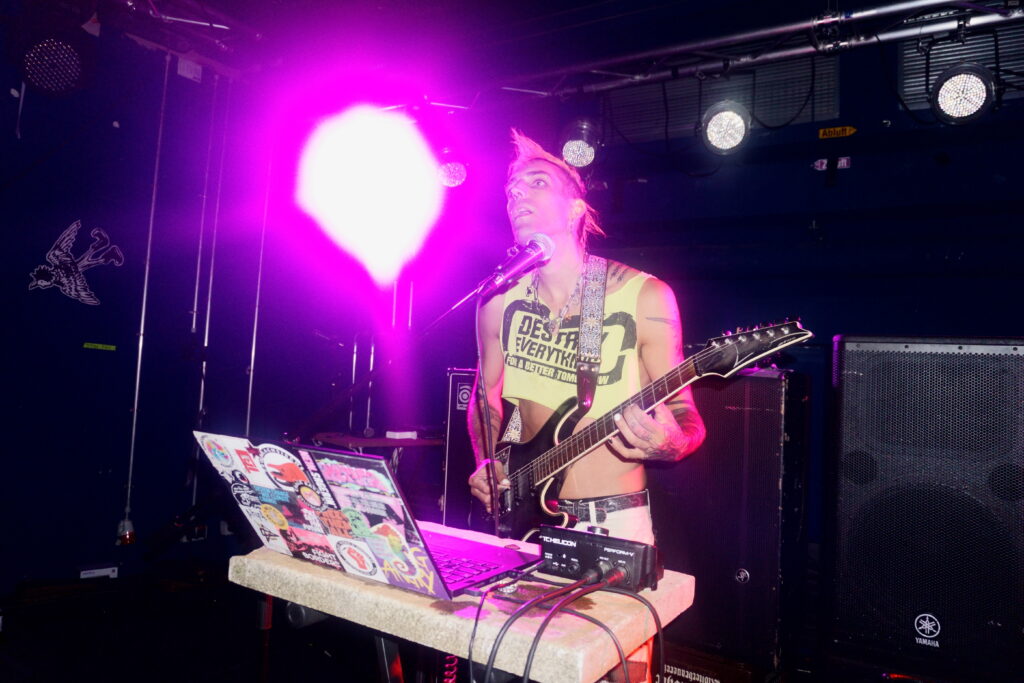 ph4nt mit orangenem Iro & neongrünem "Destroy Everything for a better Tomorrow" Croptop spielt Gitarre